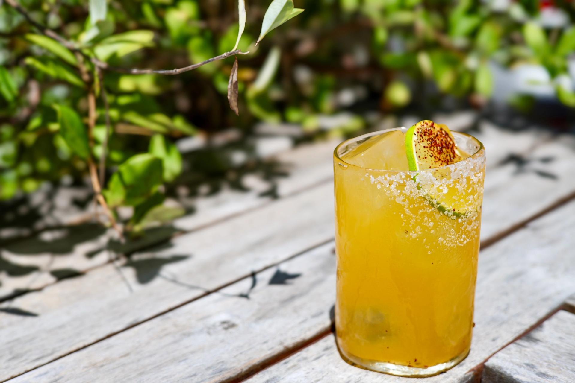 A bright yellow drink in a clear cocktail glass.