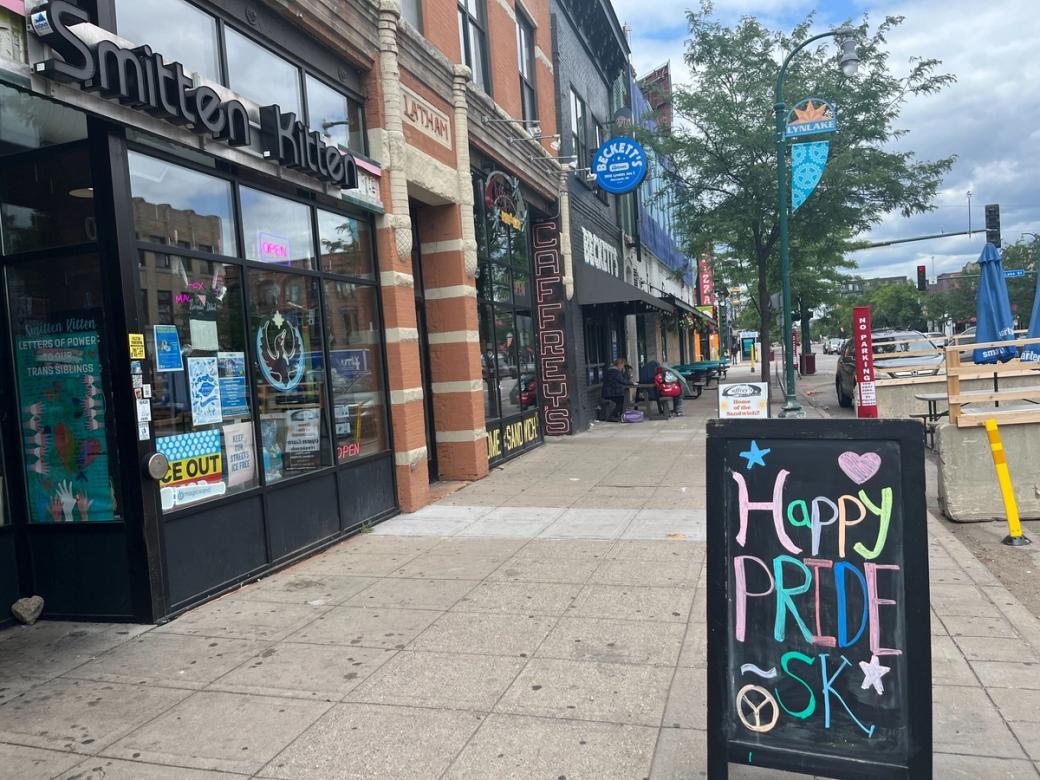Urban street lined with businesses, a-frame sign in foreground