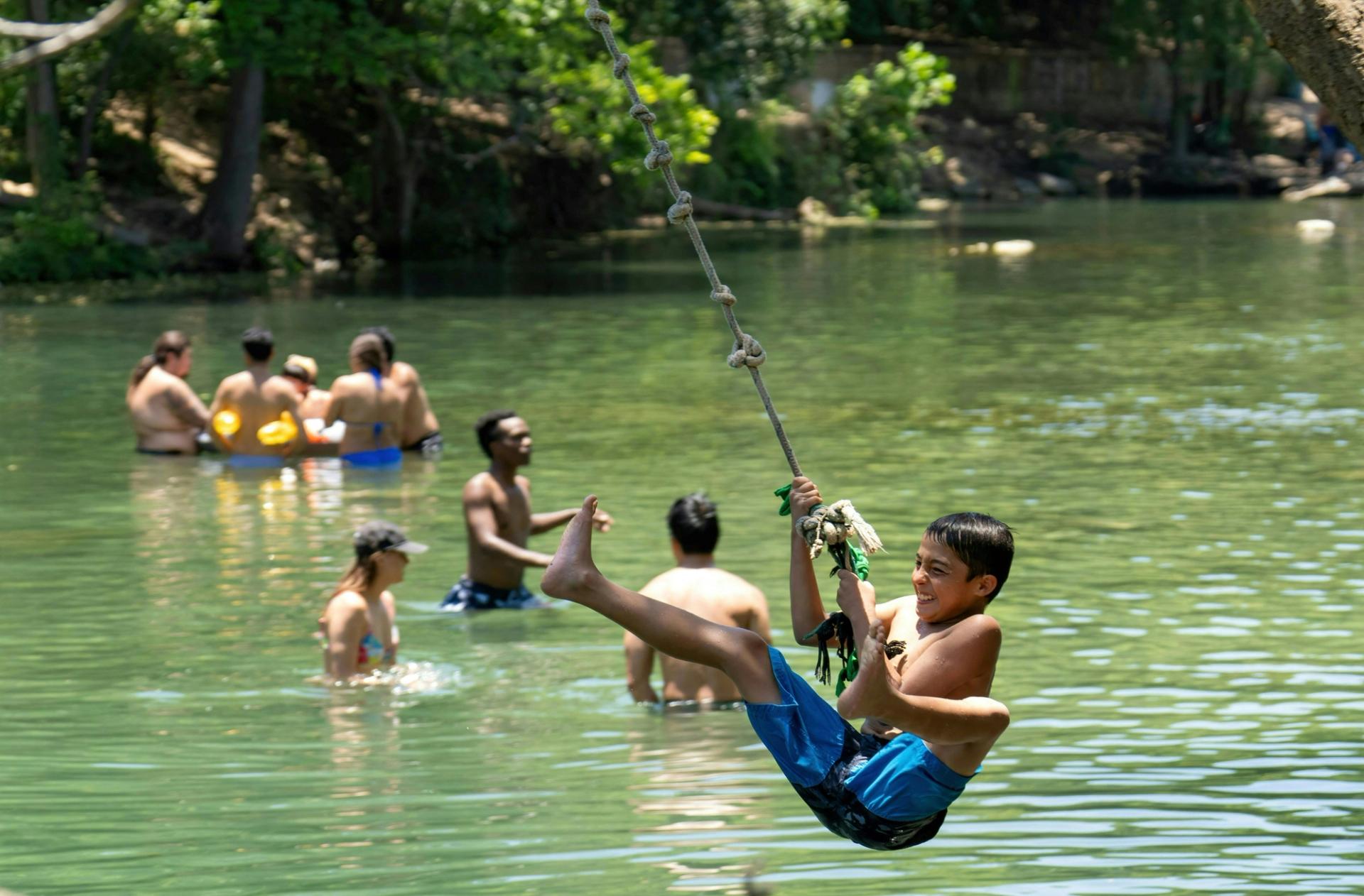 A young boy is swinging on a rope into a body of water.