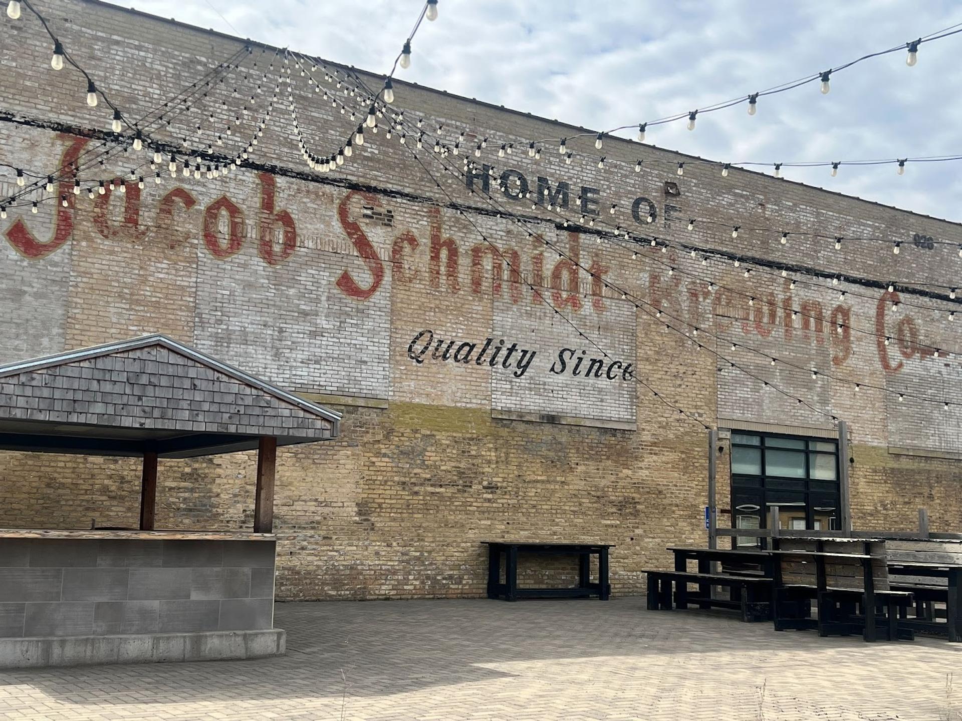 A brick building with faded paint that reads "home of jacob schmidt brewing co."