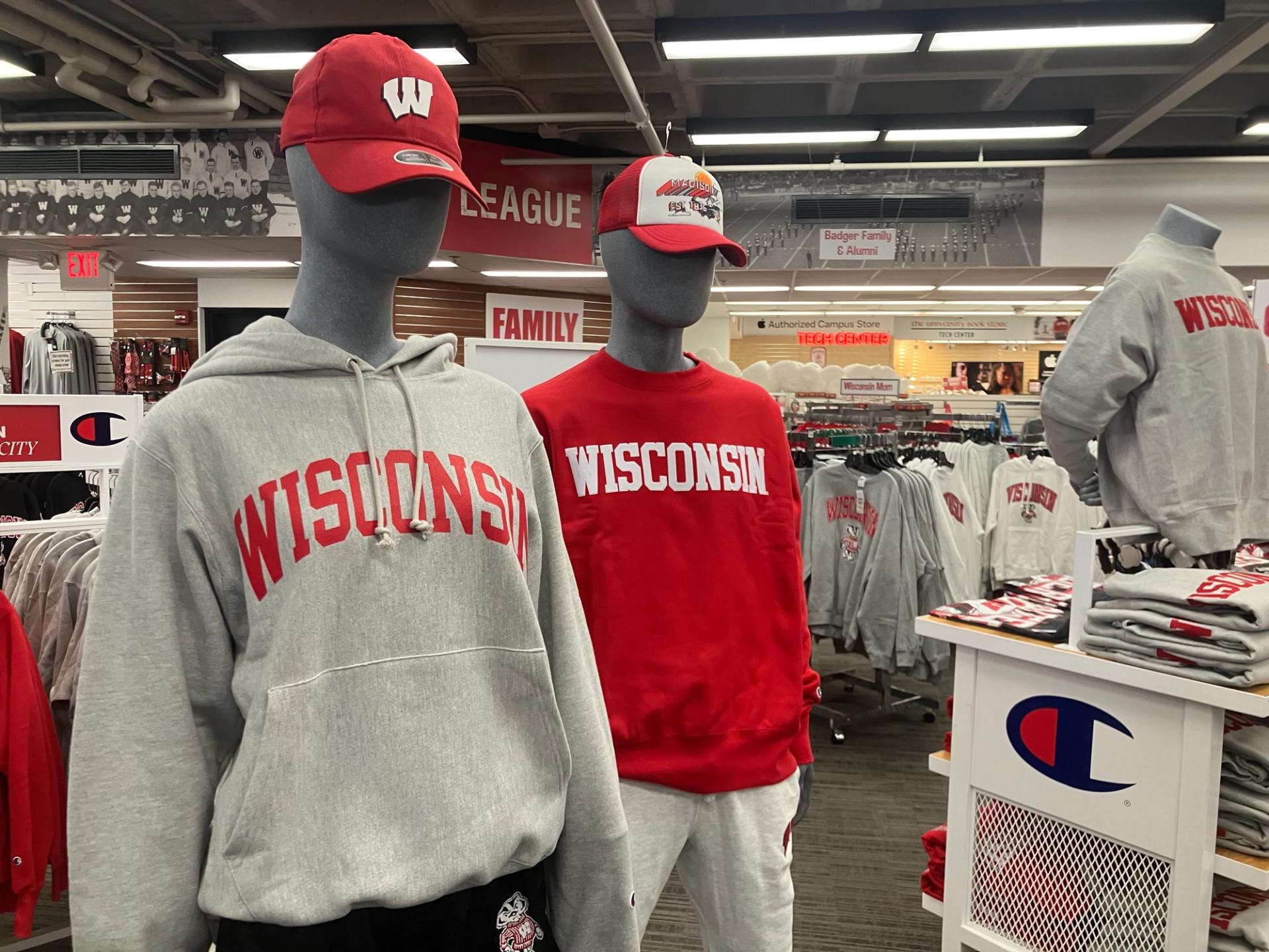 Two mannequins, one wearing a white sweater and one wearing a red hoodie.