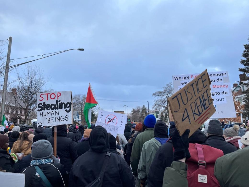 A crowd of people protesting. Signs read "stop stealing human beings" and "justice 4 Renee"