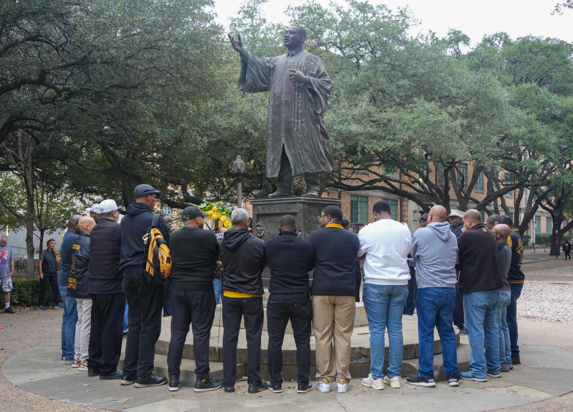 People stand around a statue of Martin Luther King Jr. on the University of Texas at Austin campus.