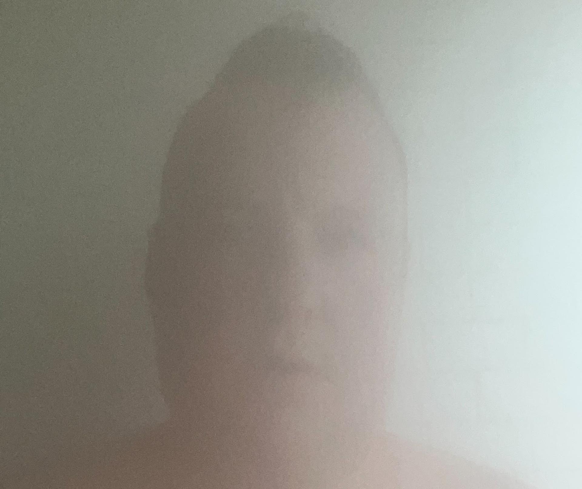A very blurred image of a man's face in a steam room.