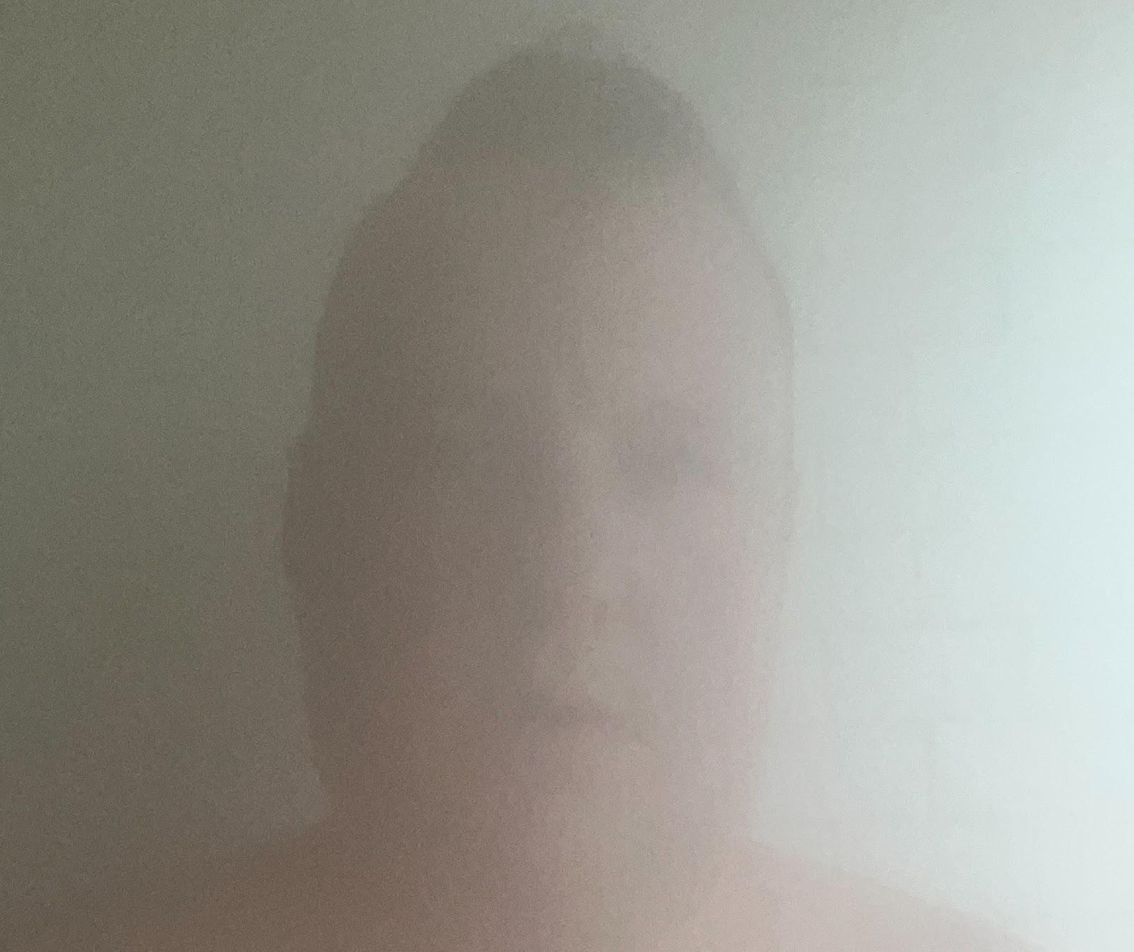 A very blurred image of a man's face in a steam room.