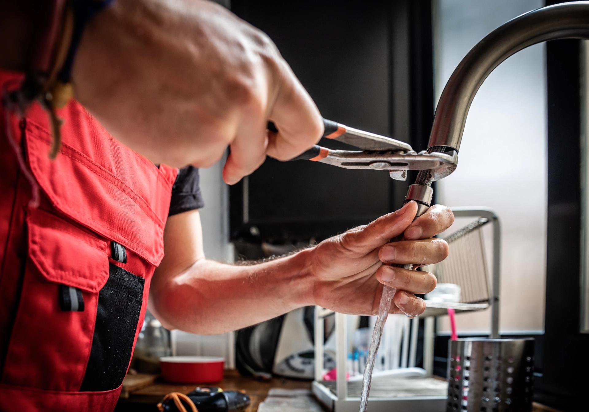 A person fixing a sink with a wrench.