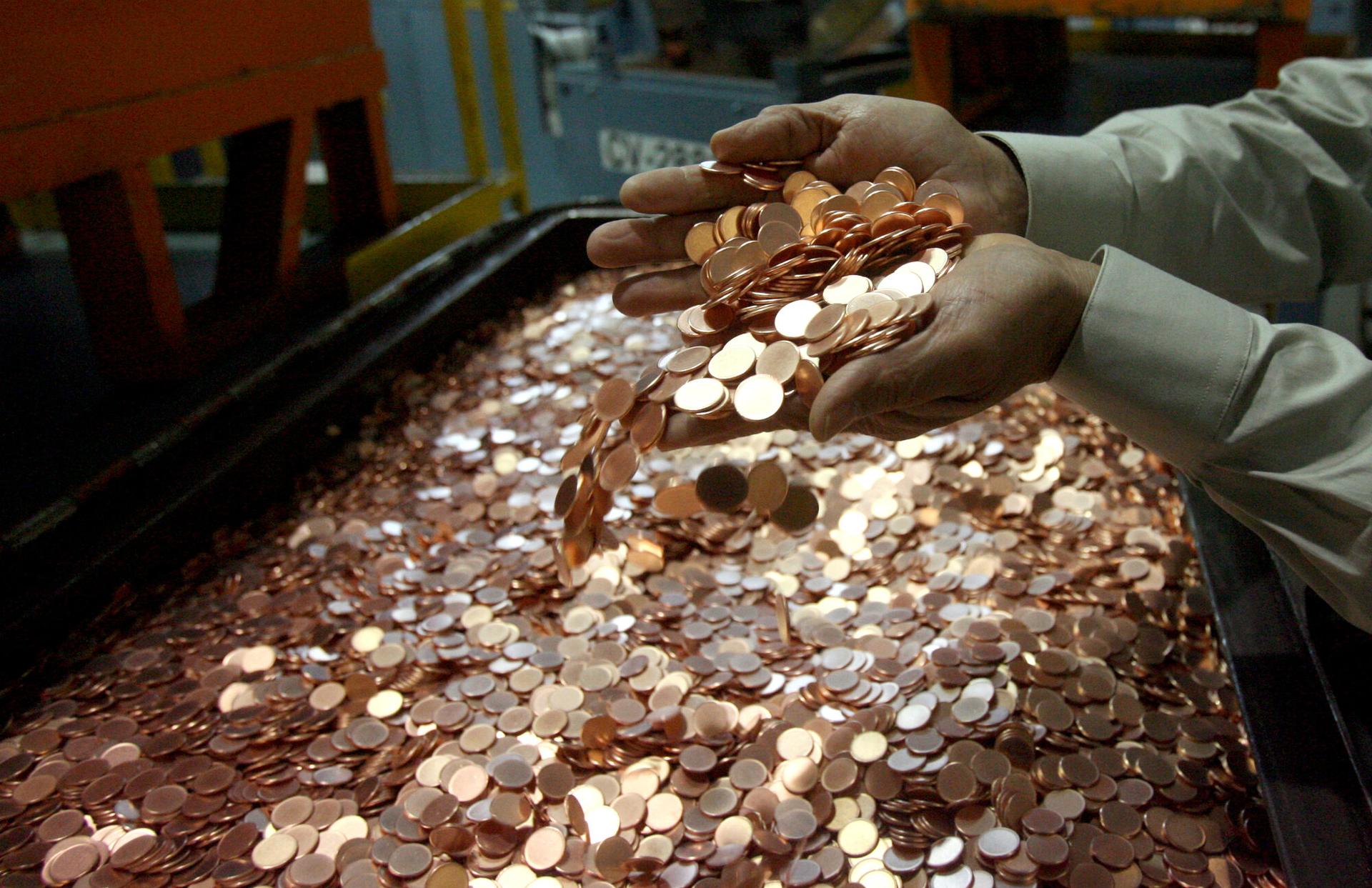 Guillermo Hernandez , of the Public Affairs Office of the Denver Mint, scoops a handful of “cents blanks” that will eventually be stamped into pennies, December 26, 2006.