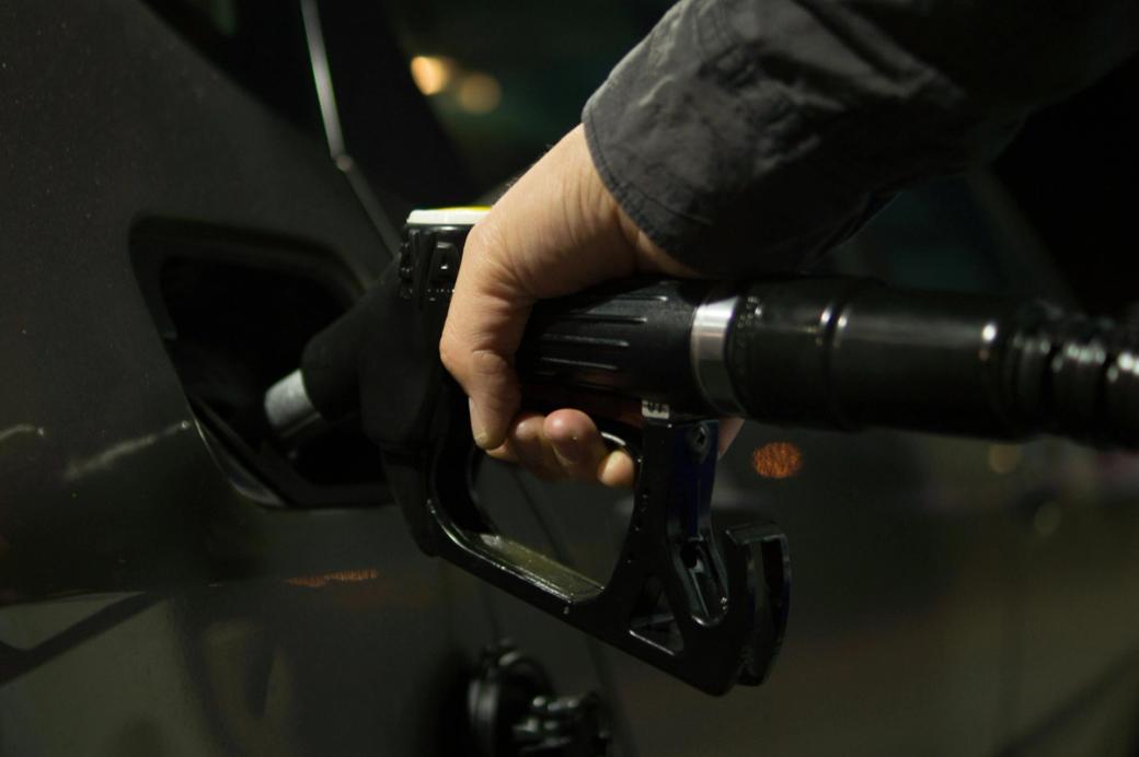 Hand holds gas pump while filling car tank.