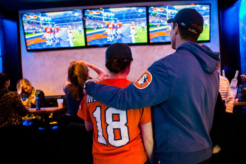 Two Denver Broncos fans watch a game at a bar.