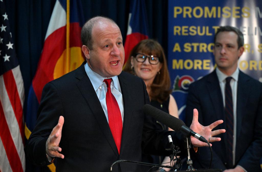 Colorado Gov. Jared Polis speaks at a press conference alongside officials.