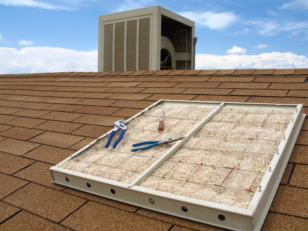 A rooftop swamp cooler, tools laying on the filter pad.