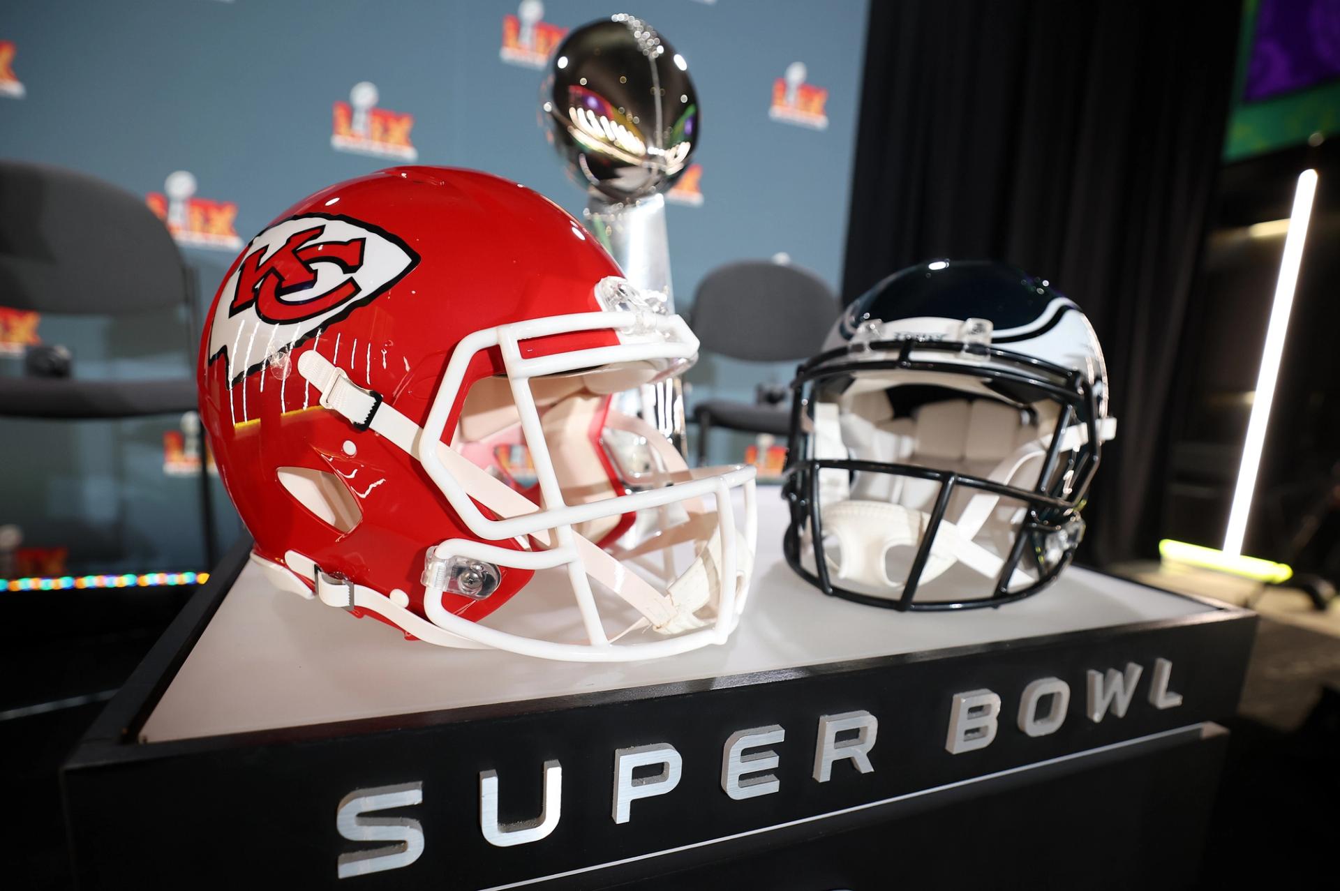 A red Chiefs helmet and black Eagles helmet sit on a platform labeled "super bowl."