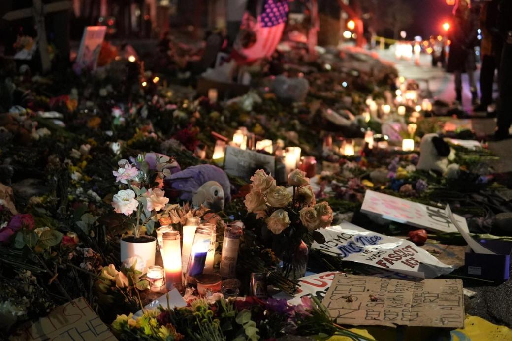 Large memorial covered in flowers, candles, and posters at night