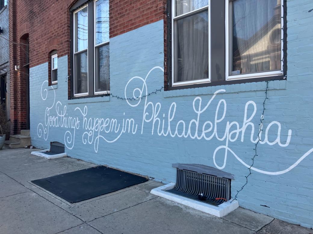 A blue wall with white lettering saying "Good things happen in Philadelphia"
