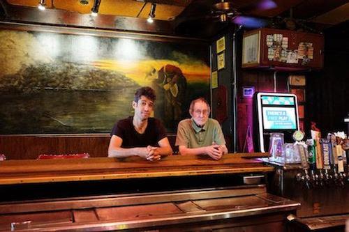 Billy Penn reporter Ali Mohsen (left) and McGlinchey’s Bar co-owner Sheldon Sokol sit behind the bar. (Abby Fritz/City Cast Philly)