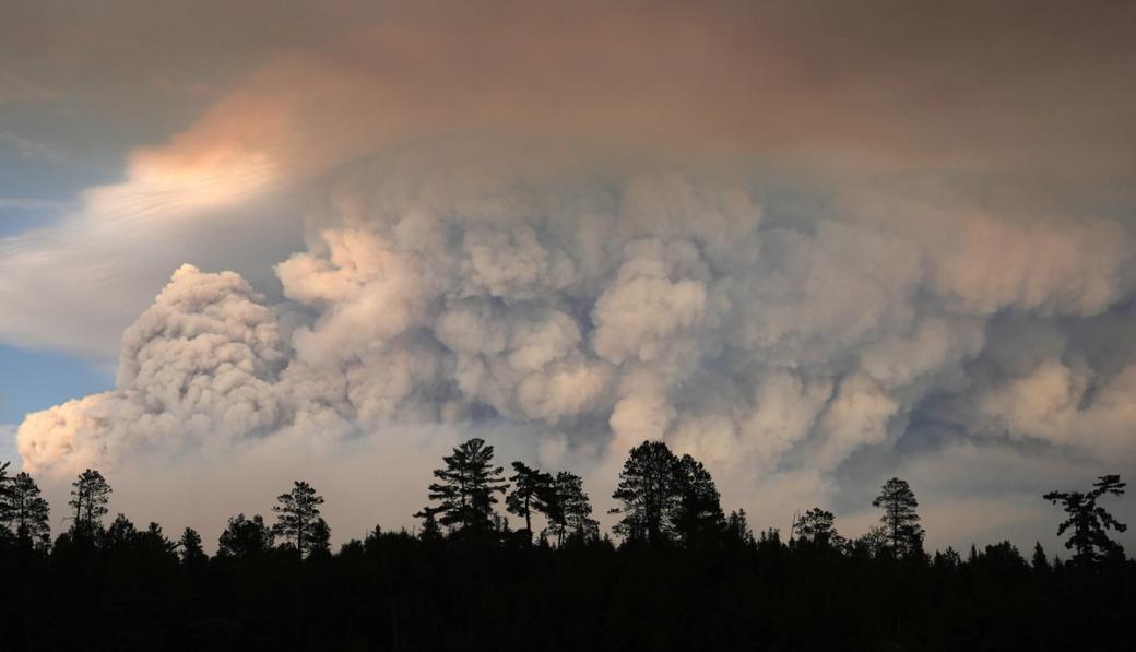 Large smoky cloud formation above skyline with trees