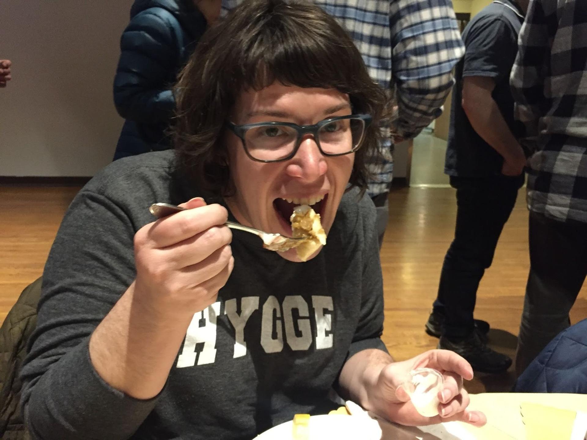 A woman with glasses biting a fish fry