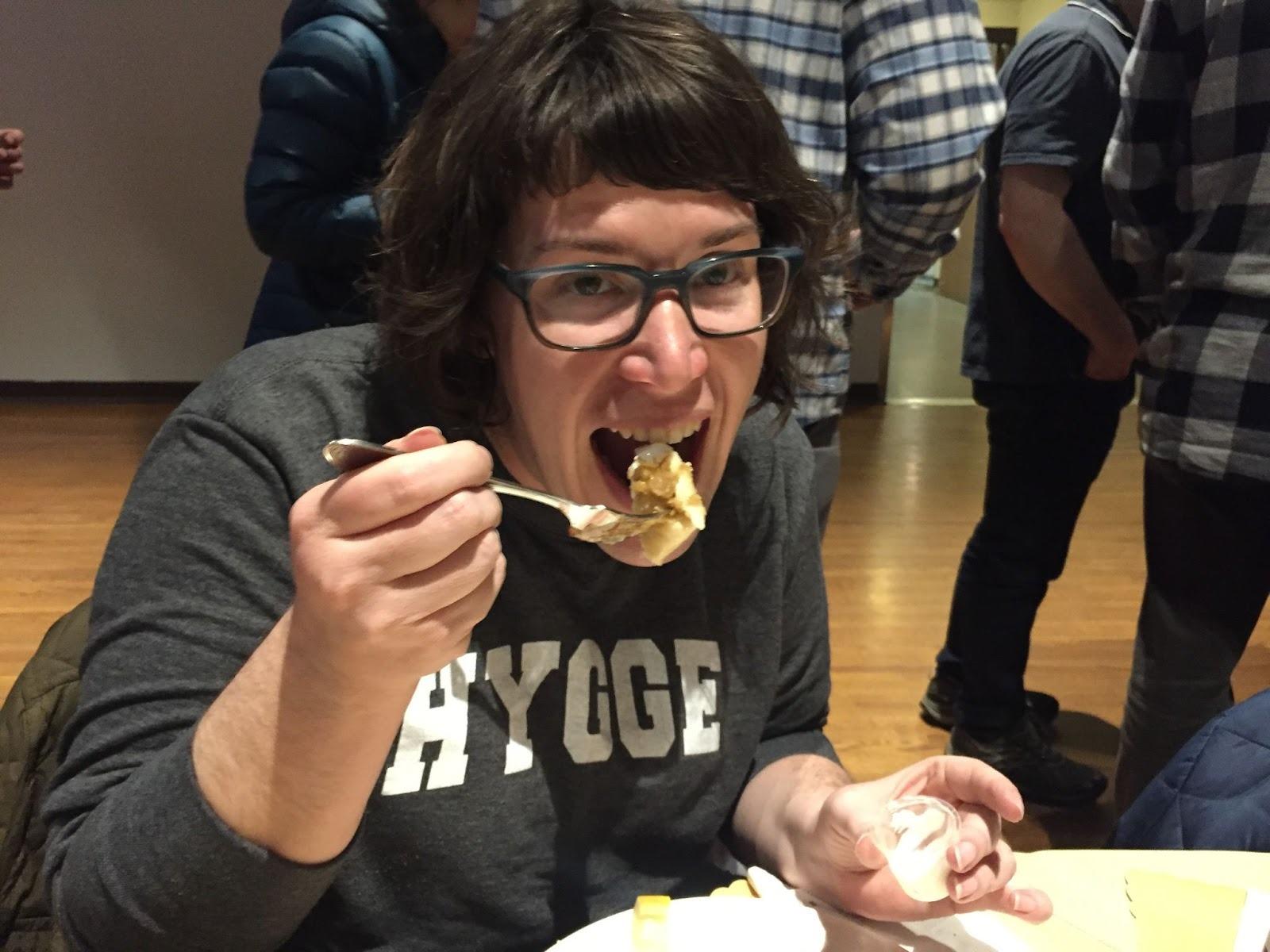 A woman with glasses biting a fish fry
