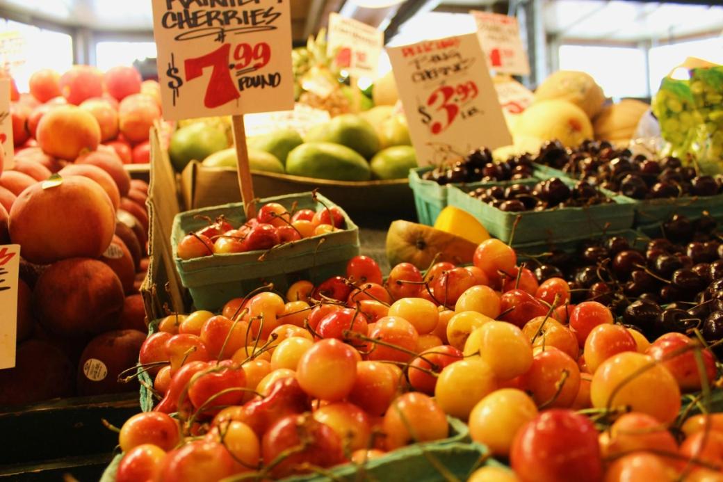 Green baskets for Rainier Cherries, with their shiny yellow and pinkish red skin, sit alongside red cherries and other fruits at Pike Place Market.