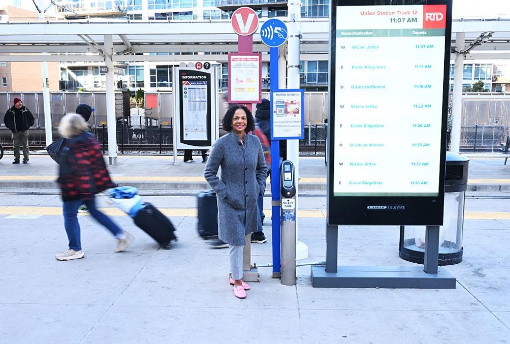 CEO of RTD Debra Johnson stands next to a tap pay station at Denver Union Station.