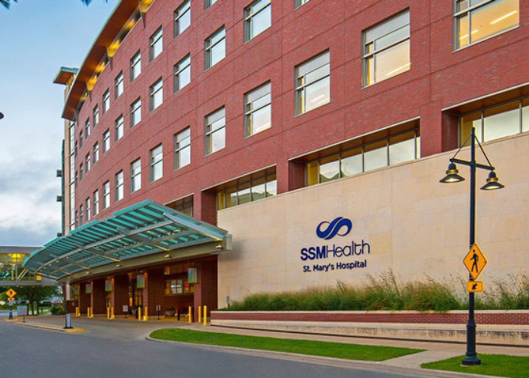 The exterior of a hospital with a road in front.