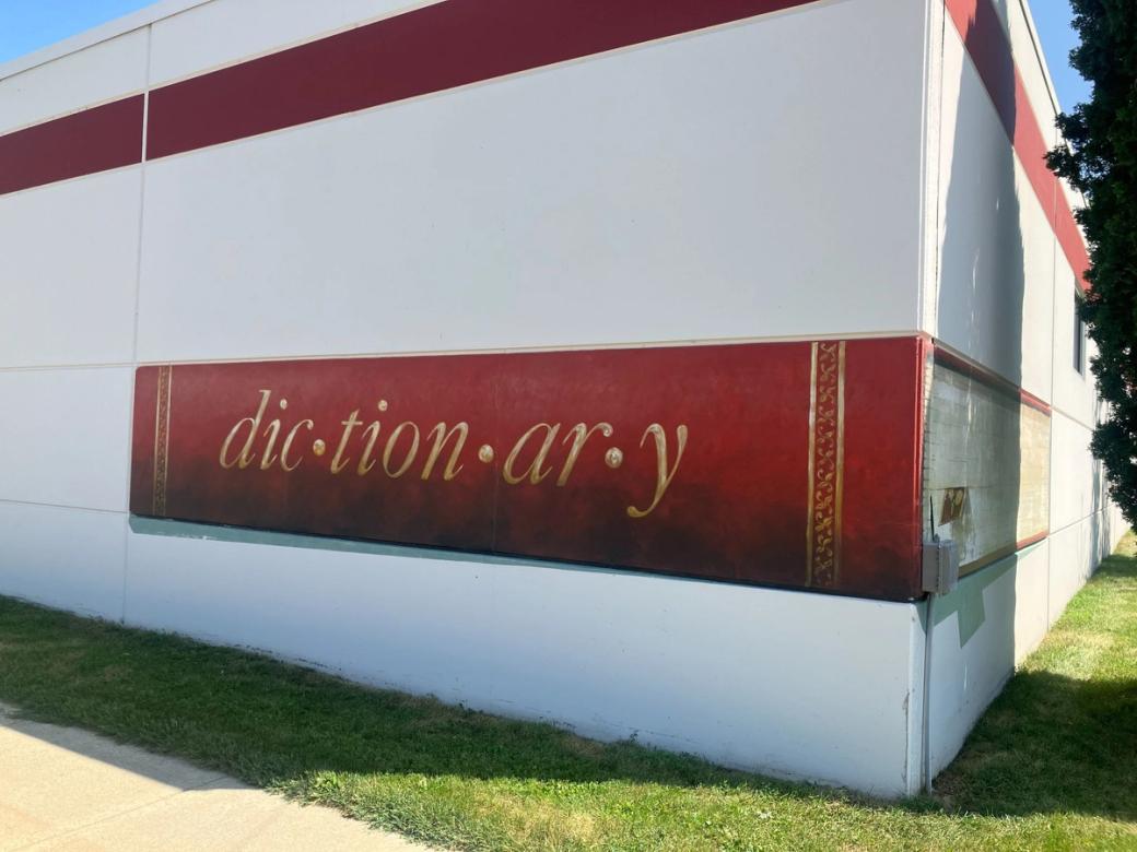 A white building with a red dictionary embedded into it.