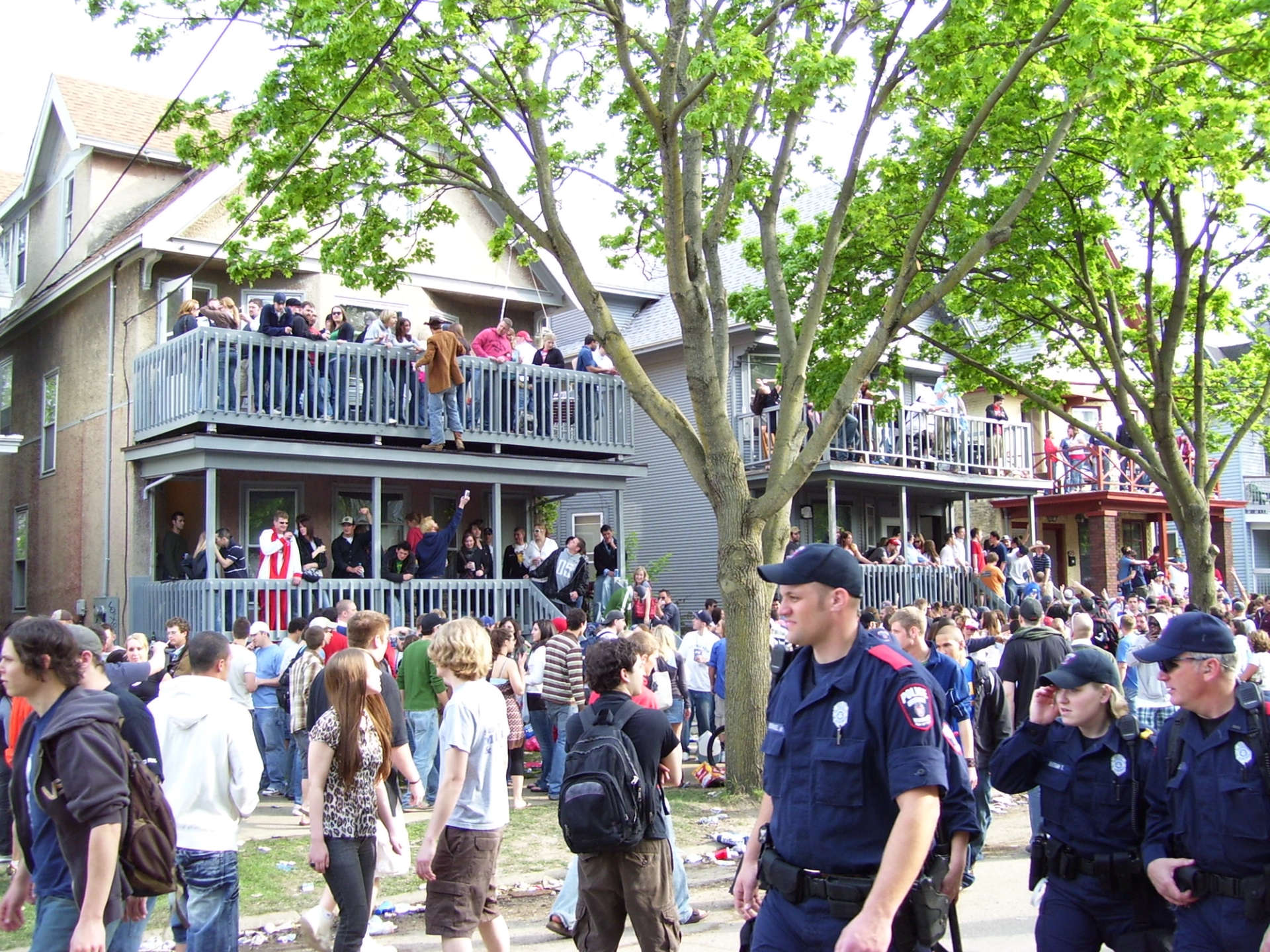Broad picture showing people and police officers on house balconies and on the street at the 2007 Mifflin Street Block Party.