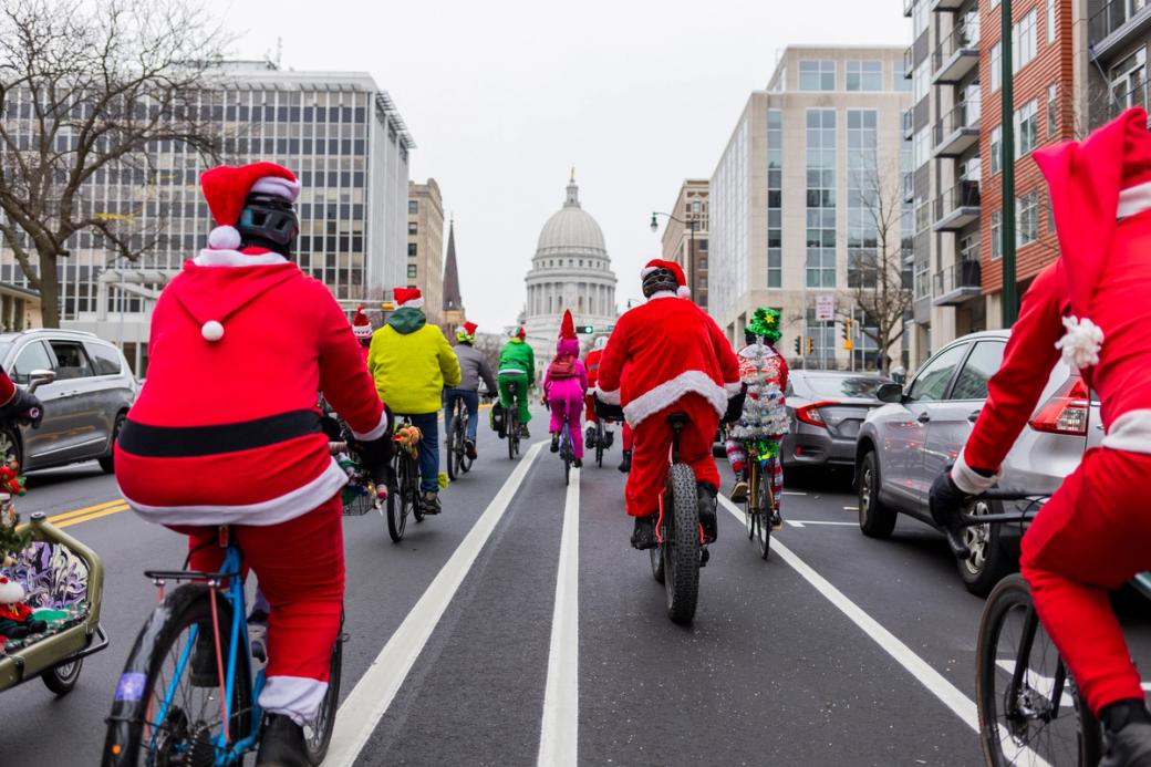 Cyclists, some in Santa suits, riding on a city street. 