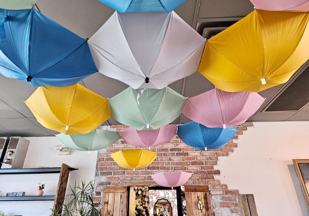 A group of pastel umbrellas hang upside down from a ceiling.