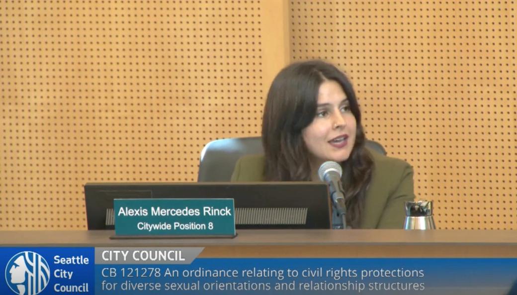 Alexis Mercedes Rinck sits behind her name placard at her desk in City Council and speaks into a mic during the presentation of the new civil rights protections ordinance.