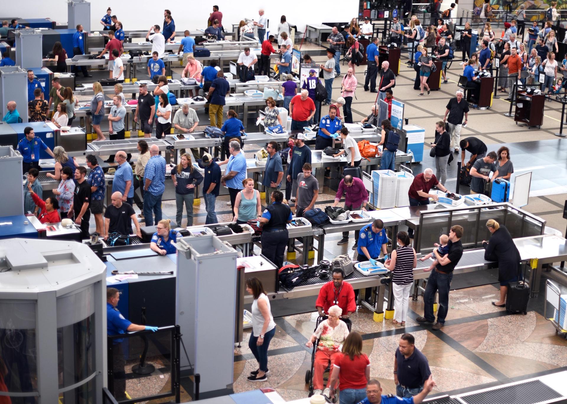 A crowd of people in line at scanning machines at an airport.