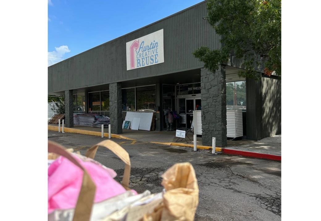 The outside of a building. A sign reading "Austin Creative Reuse" hangs above the entrance door.
