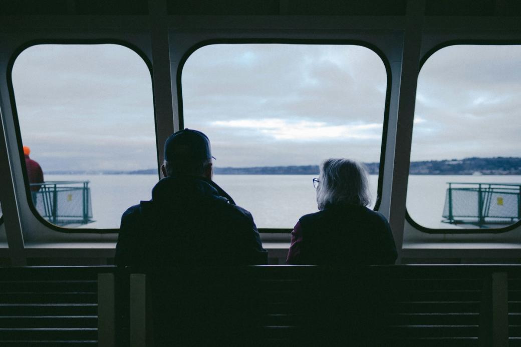Two elderly people looking out the window on a ferry