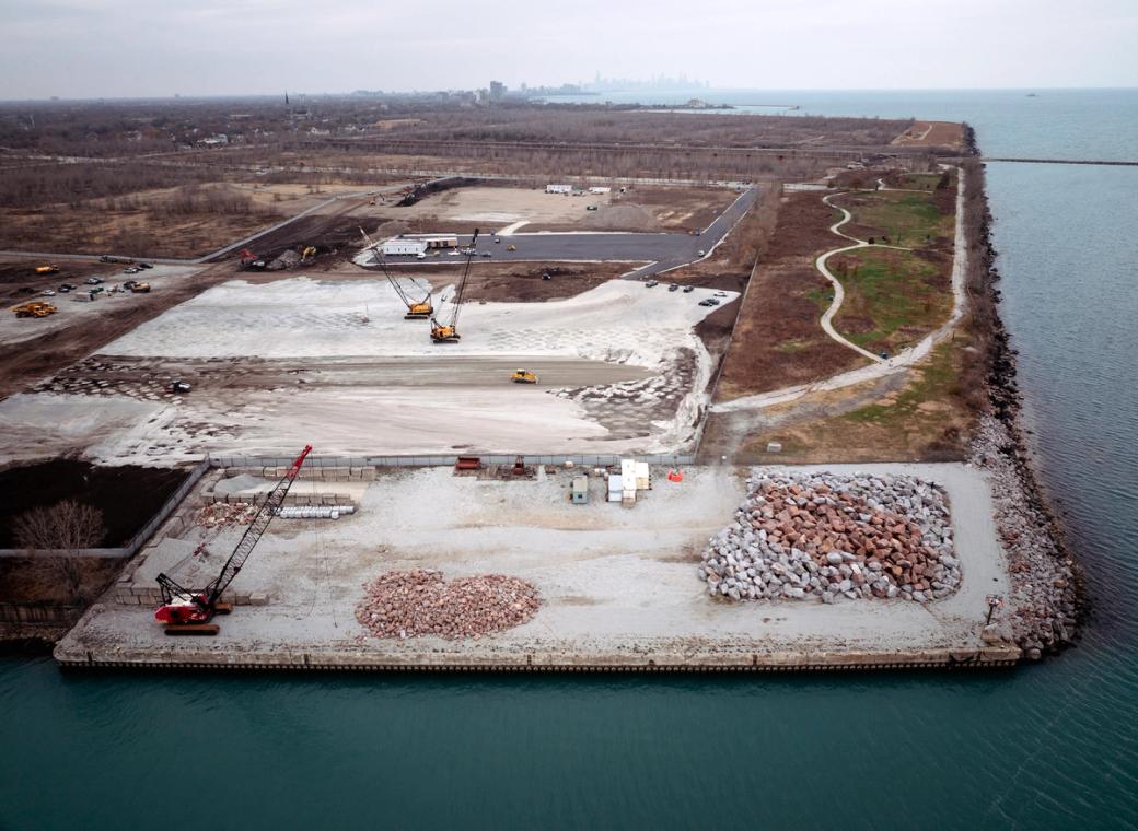 An aerial view of a work site by the lake. The grass is red and orange  and on the work site there is a crane