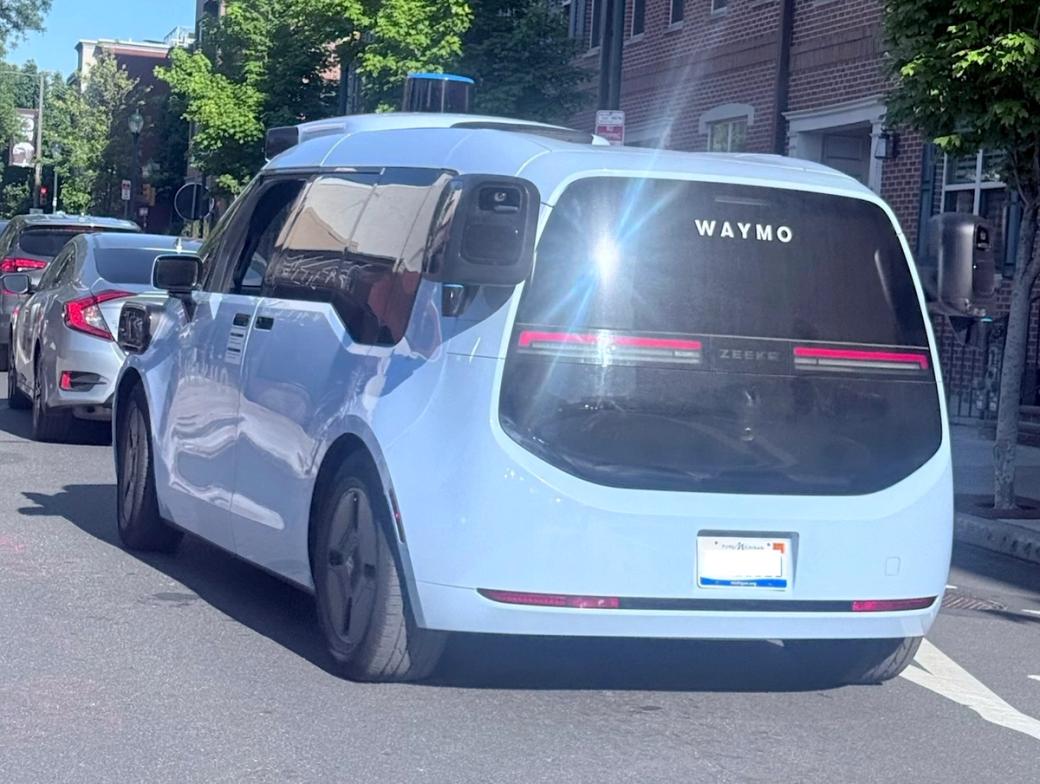 Blue Waymo van driving up Philly street