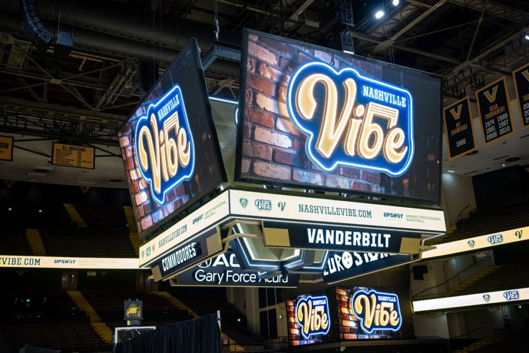 A set of large screens hanging in a basketball stadium