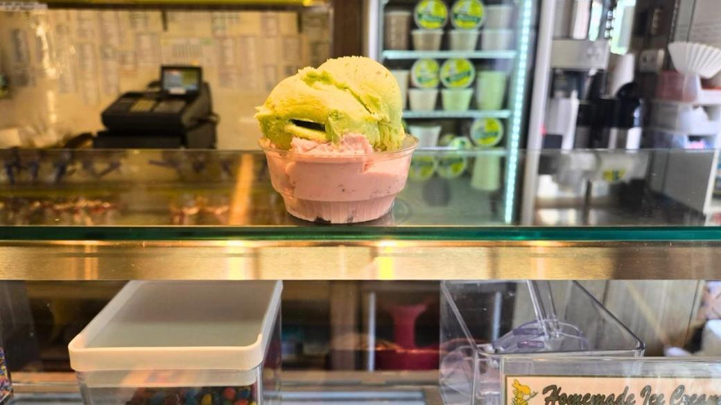 A green ice cream in a pink cone on a glass top