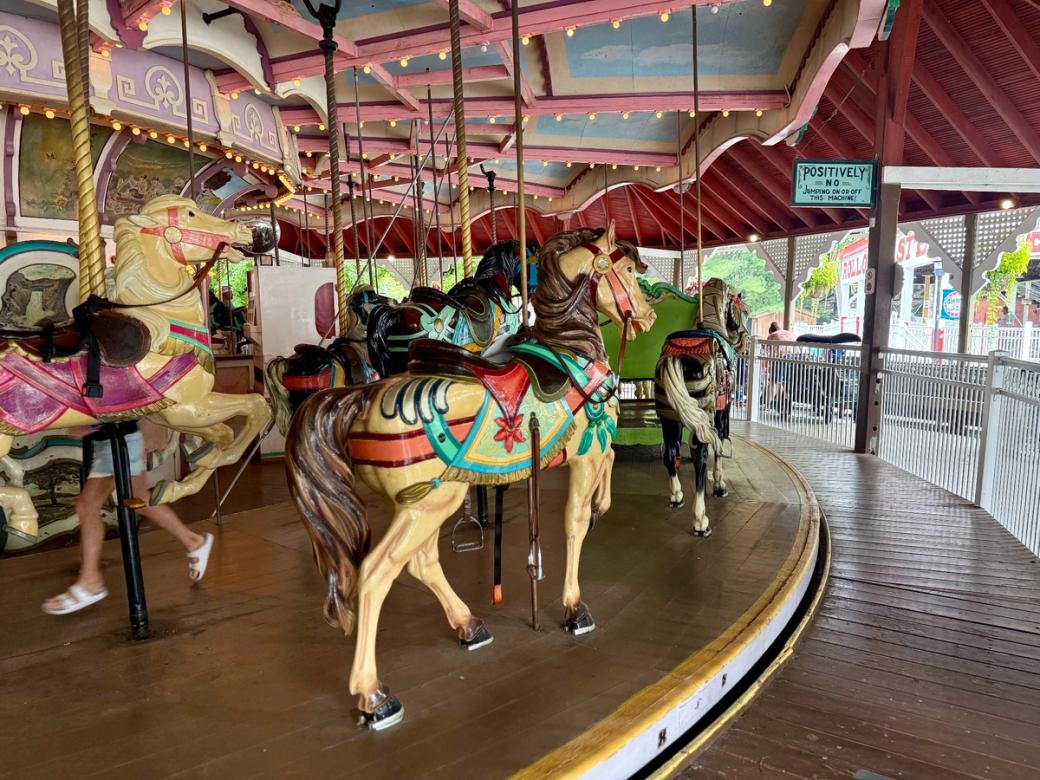 Colorful painted horses are arranged in a circle on a wooden carousel.
