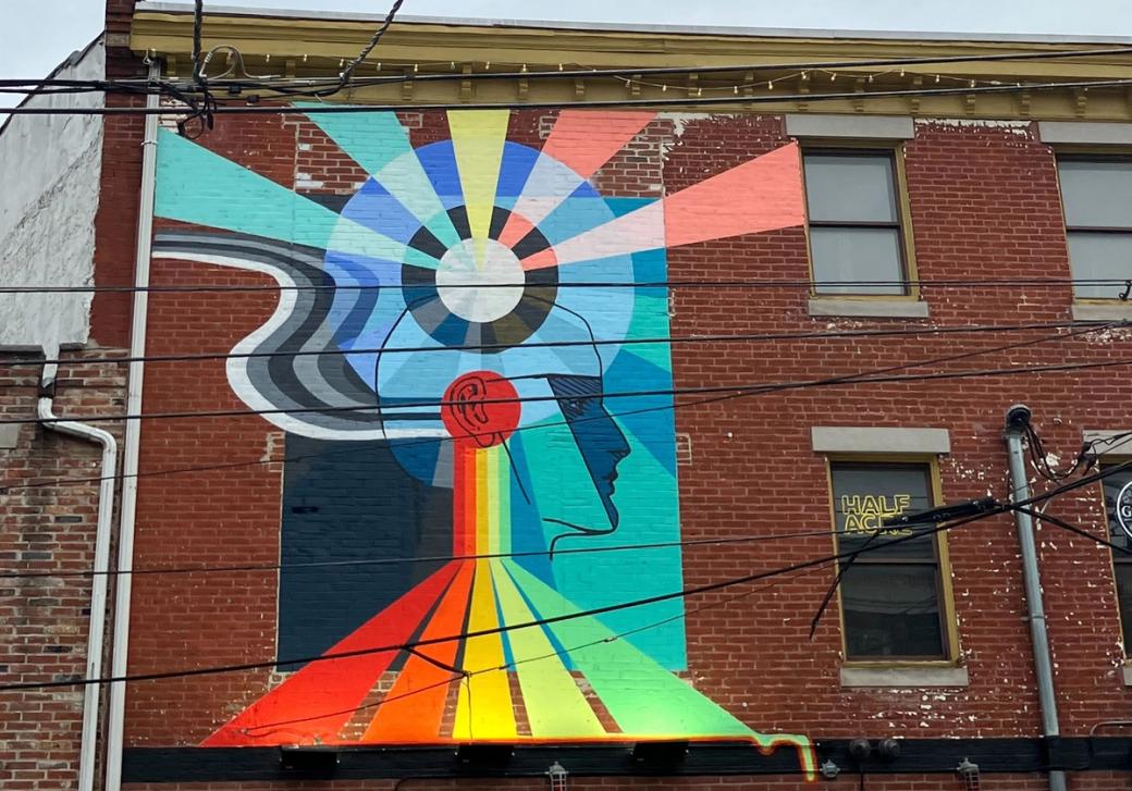 A multicolored mural of a human head listening to a record with bright ways extending outward