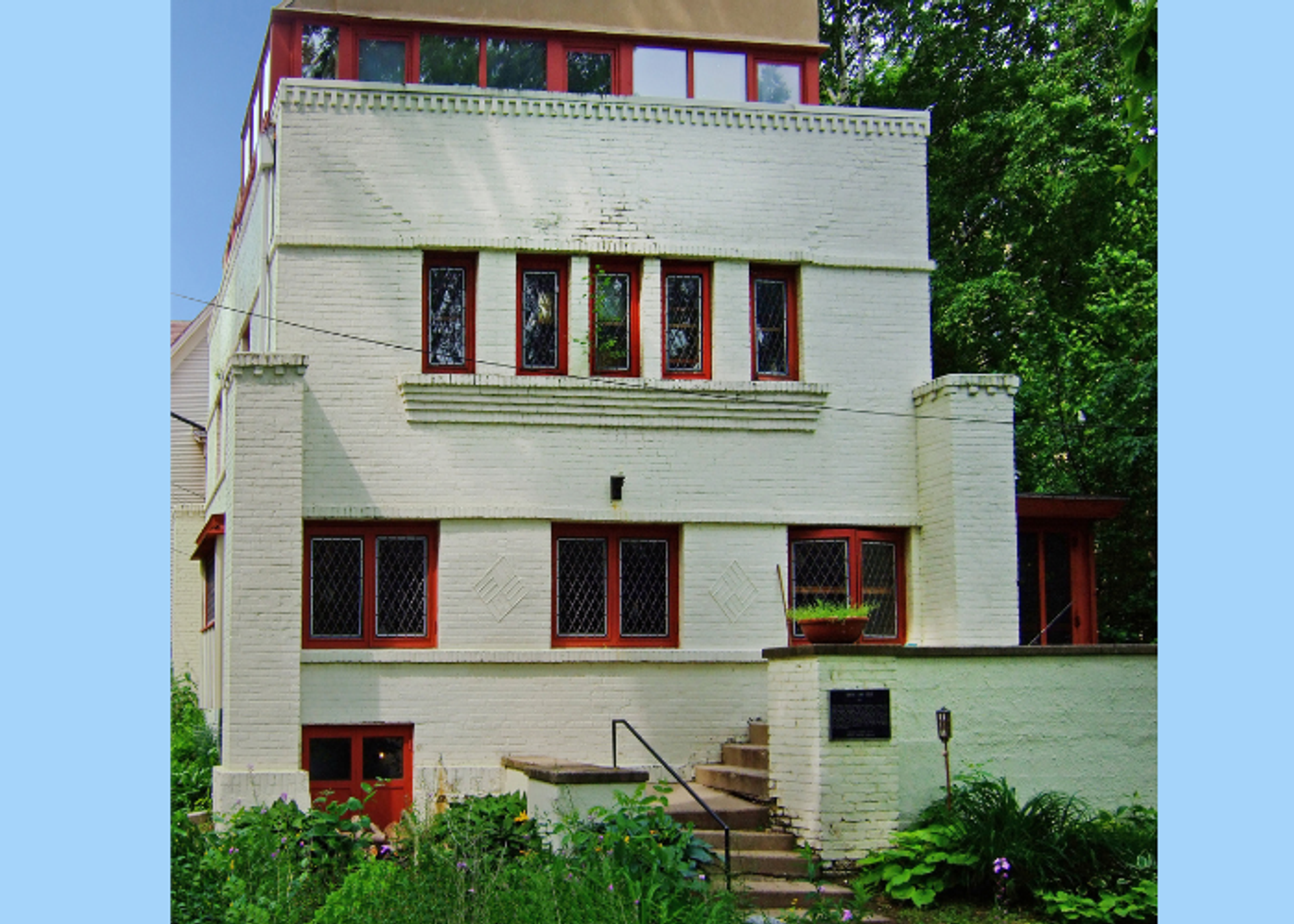 A boxy gray building with red window trims