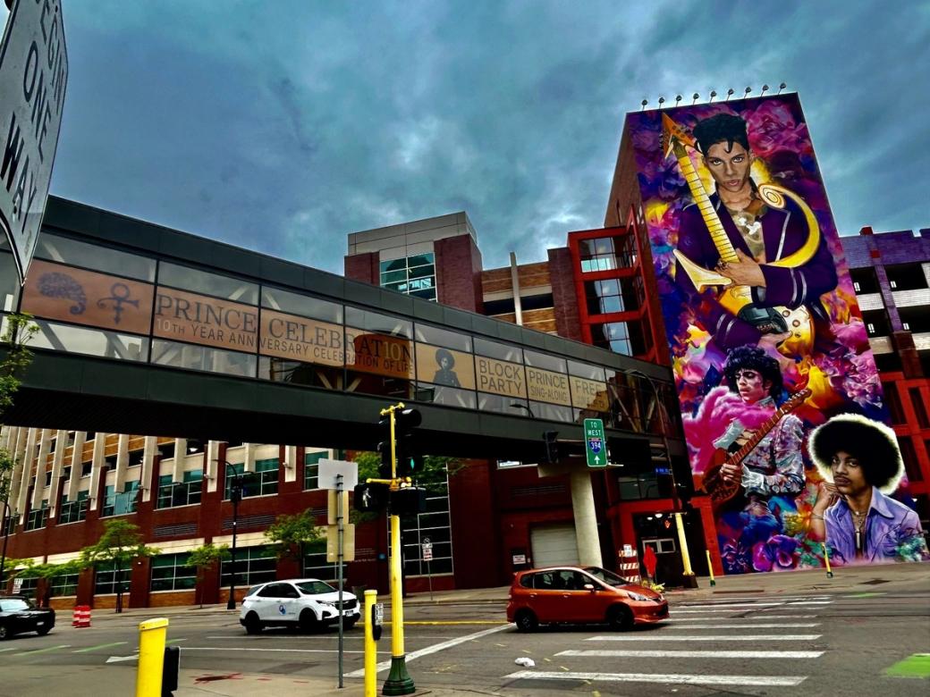 Street-level view of colorful mural featuring musical artist Prince on urban street