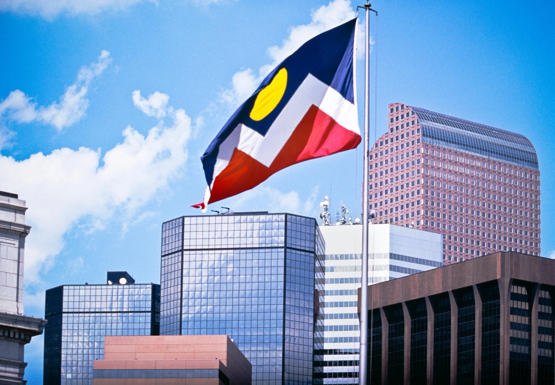 The official Denver flag flies against a backdrop of the city.