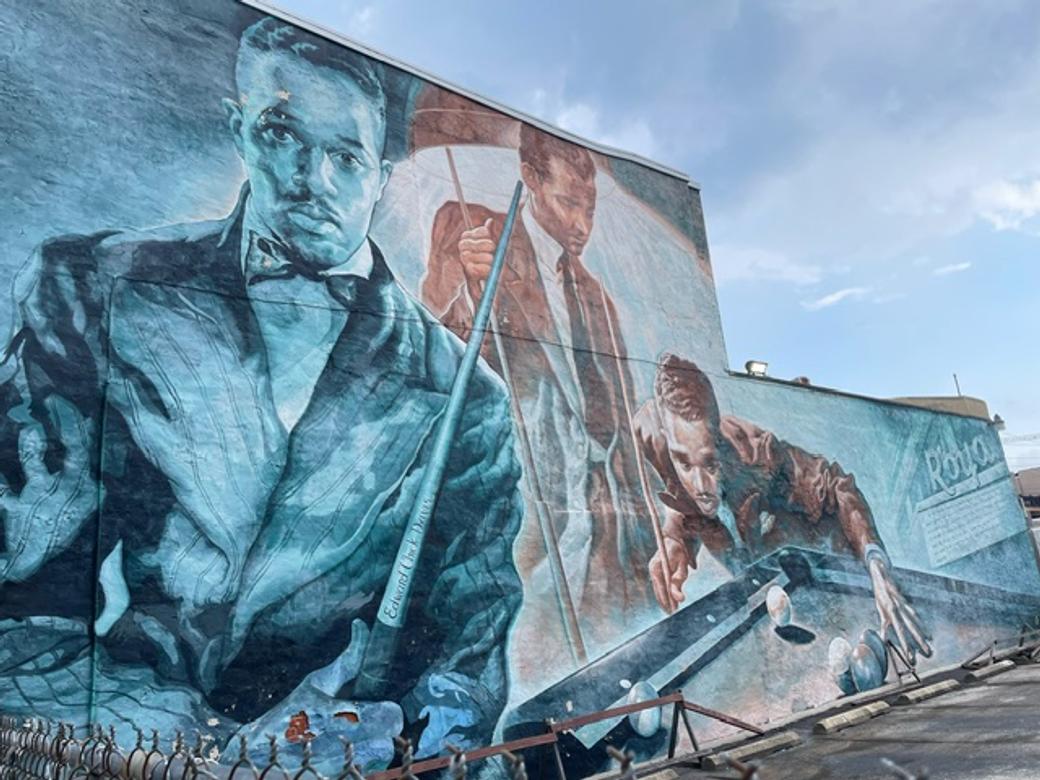 A mural of the same man shown three times, including playing pool.