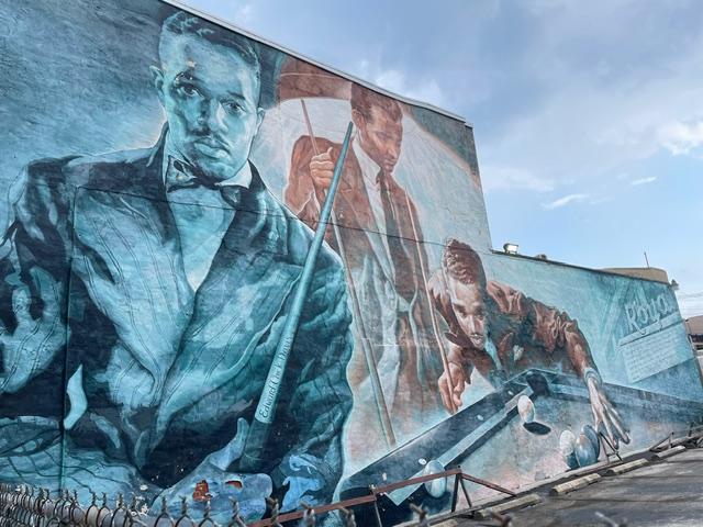 A mural of the same man shown three times, including playing pool.