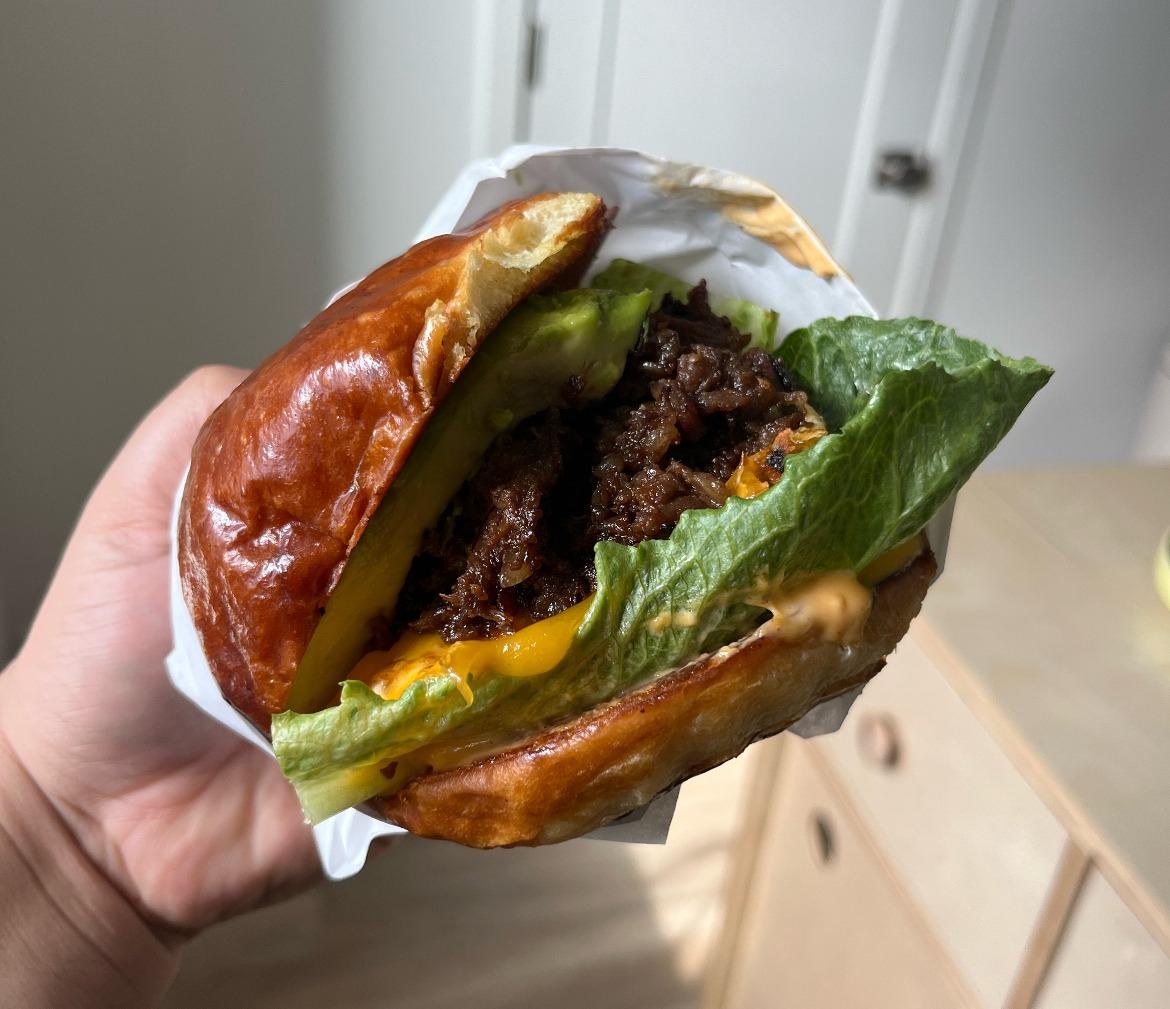 Woman's hand holding a bulgogi breakfast sandwich from Grumpy Dough.
