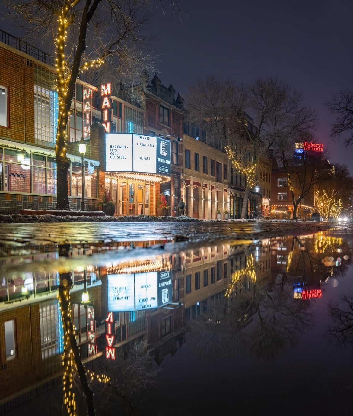 A wet street at night time outside of the The Main Theater