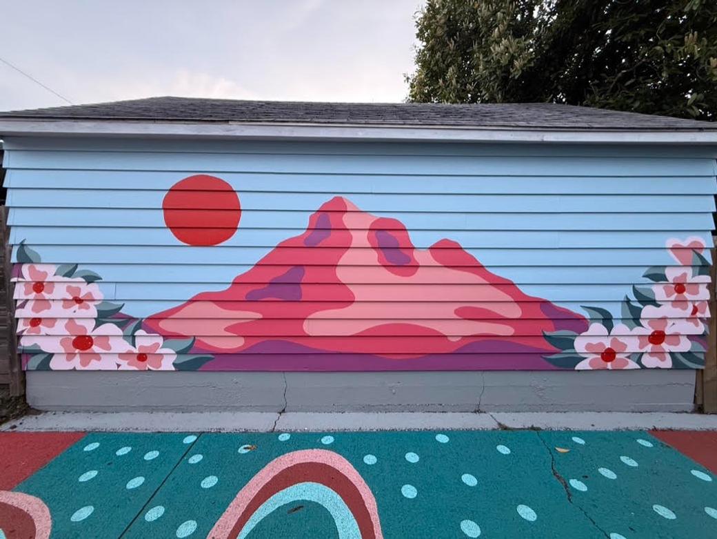 a mural depicting a pink-red version of Mt. Hood with a red sun and dogwood flower