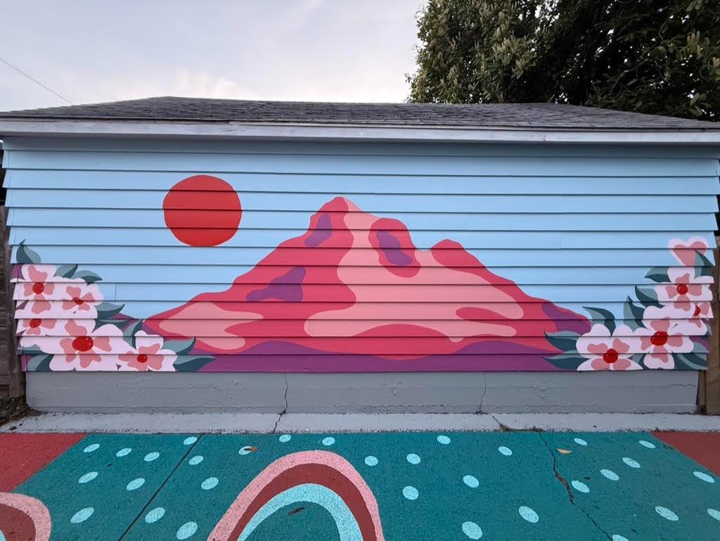a mural depicting a pink-red version of Mt. Hood with a red sun and dogwood flower