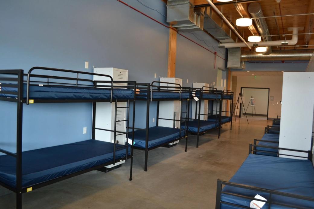 A row of bunk beds with black bed frames and blue mattresses.