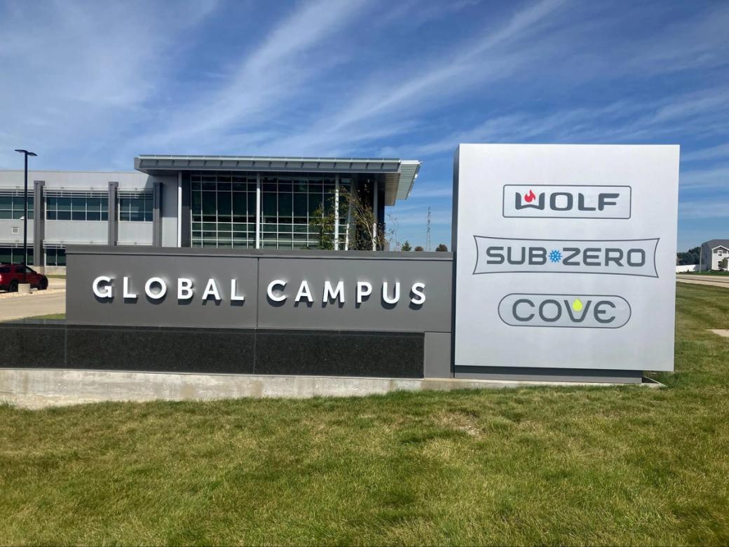 A grey building with the words "Global Campus" on it and a sign that lists "Wolf" "Sub Zero" and "Cove."